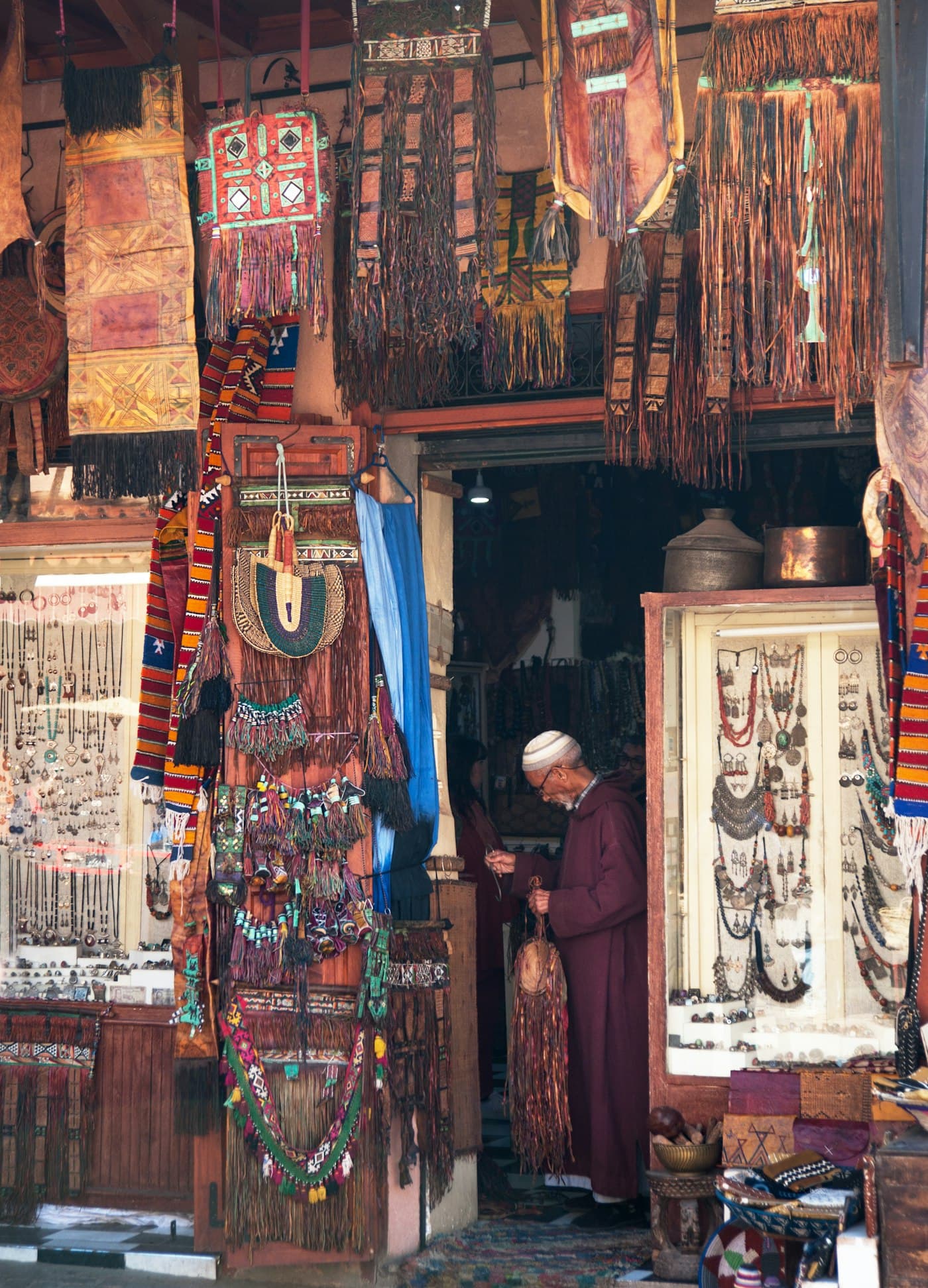 A shopkeeper in the doorway of a market shop full of goods